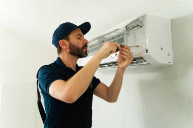 Profesyonel hvac teknisyeni servis çağrısı sırasında minisplit klima sistemini korumak için tornavida kullanıyor.
