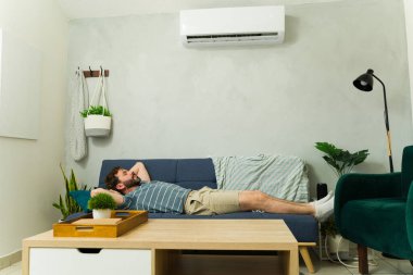 Kanepede uzanan adam, sıcak bir yaz gününde sıcak havanın tadını çıkarıyor.