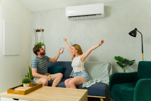 Cheerful couple relaxing on a comfortable sofa, enjoying the refreshing coolness of air conditioning while beating the summer heat at home