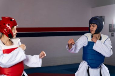 Dövüşçüler tekvando antrenmanına katılıyorlar, iyi donanımlı bir spor salonunda idman yaparken koruyucu giyiyorlar.
