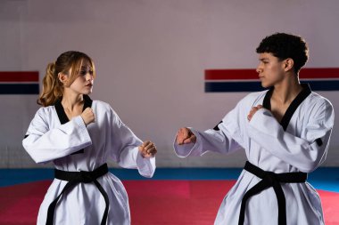 Spor salonunda tekvando antrenmanı yapan Doboks ve siyah kuşaklı iki sporcu yeteneklerini ve dövüş sanatları eğitimine adanmışlıklarını sergiliyorlar.