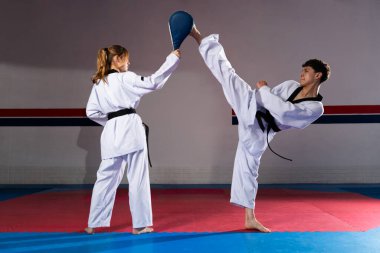 Tekvando dövüşçüleri dövüş sanatlarının gücünü ve hassasiyetini göstermek için bir dojoda tekmeleme teknikleri uyguluyorlar.