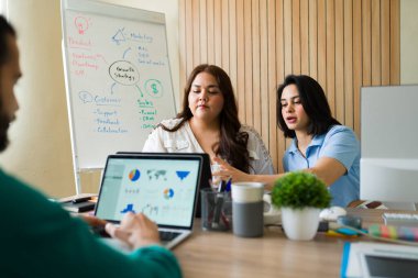 Çağdaş bir ofis ortamında verileri analiz eden ve verimli bir toplantıda işbirliği yapan pazarlama uzmanları