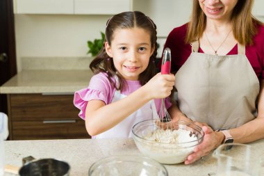 Mutfakta annesiyle cam kasede malzemeleri çırpıyor, birlikte pişiriyor ve yemek yapmayı öğreniyor.
