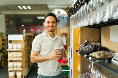 Gülümseyen İspanyol müşteriler toptan alışveriş yaparken içi fındık dolu plastik bir kavanozu tutuyorlar.