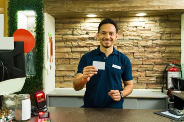 İspanyol erkek kasiyer markette ya da süpermarkette kasiyerlik yaparken boş bir kart gösteriyor.