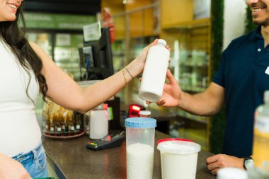 Sıfır atık dükkanından alışveriş yapan neşeli müşteri, mağaza yardımcısından yeniden kullanılabilir konteynır alıyor.