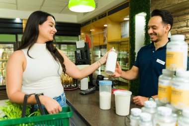 Neşeli müşteri bakkal alışverişi yapıyor ve bir marketin kasasındaki kasiyere mal veriyor.