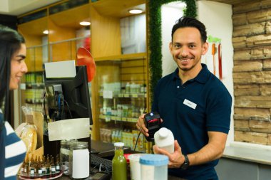 İspanyol kasiyer, bir süpermarketin kasasında müşterilere verimli ve yardımcı hizmetler sunarak bakkaliyeleri tarıyor.