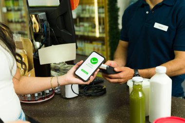 Alışveriş yapan kişi bakkal kasasında ödeme terminali olan cep telefonu ödemesini tamamlıyor.