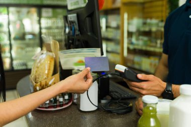 Alışveriş yapan kişi, markette kredi kartıyla ödeme yapmış. Posta kutusunun yanında tutuyor.