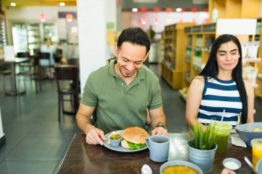 Neşeli İspanyol bir adam ve kadın bir restoran masasında sağlıklı bir öğle yemeğinin tadını çıkarıyorlar, dengeli bir hayat sürüyorlar.