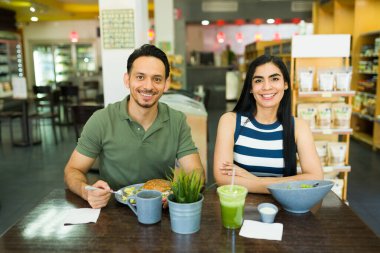 Mutlu İspanyol çift bir restoranda lezzetli ve sağlıklı bir yemeğin tadını çıkarıyor, taze salata ve hamburger yerken gülümsüyorlar.
