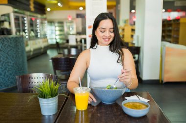 Portakal suyu olan bir restoranda taze salata yiyen İspanyol kadın, sağlıklı bir öğle yemeği molası veriyor.