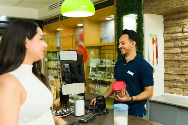 Dost canlısı süpermarket tezgâhtarı kasadaki kadın müşterileri tarıyor, bir markette mükemmel hizmet veriyor.