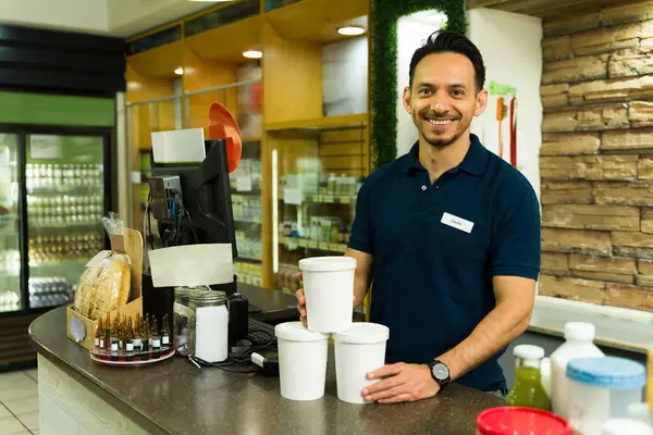 Bir marketin kasasında hazır yemek siparişi veren mutlu bir işçi müşterilere siparişleriyle servis yapmaya hazır.