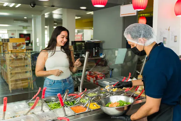 Müşteri, salata barından özel salata sipariş ediyor. Aşçı da onun talimatlarına göre yemeği hazırlıyor.