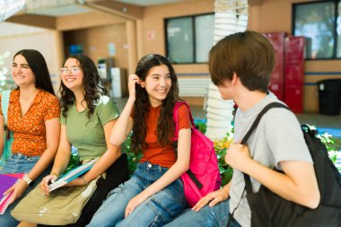 Bir grup neşeli lise öğrencisi tatilde sohbet ediyor, okul yaşam tarzlarının ve eğitiminin tadını çıkarıyorlar.