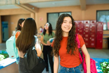 Bir grup lise öğrencisi okul bahçesinde mola veriyor, sohbet ediyorlar ve canlı bir eğitim yaşam tarzı sergiliyorlar.