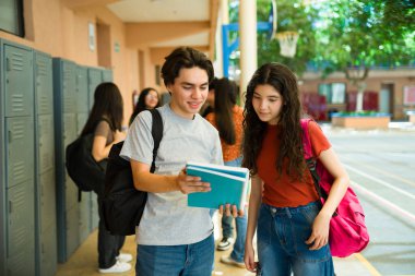 Okul koridorunda ev ödevleri konusunda işbirliği yapan gençler, dersler arasındaki fikir ve notları paylaşıyorlar.