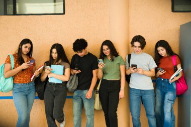 Sınıflar arasında akıllı telefonlarını kullanan, sosyal medyadan ve çevrimiçi iletişimden zevk alan çeşitli lise öğrencileri grubu.