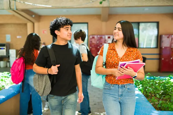 Latin öğrencilerin sohbet etmesi ve kalabalık bir okul koridorunda yürümesi, arkadaşlığın ve bağlantının keyfini çıkarması.