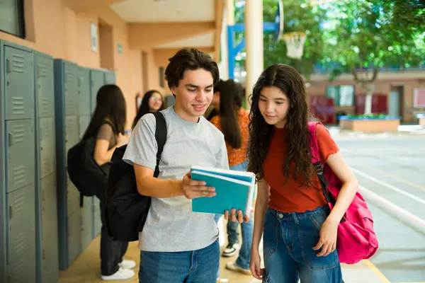 Okul koridorunda ev ödevleri konusunda işbirliği yapan gençler, dersler arasındaki fikir ve notları paylaşıyorlar.