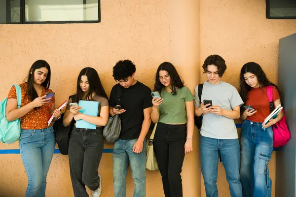 Sınıflar arasında akıllı telefonlarını kullanan, sosyal medyadan ve çevrimiçi iletişimden zevk alan çeşitli lise öğrencileri grubu.