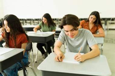 Çeşitli lise öğrencilerinden oluşan bir grup, yazılı sınav ya da sınava girerken konsantre oluyorlar.