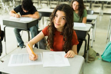 Kabul sınavı için cevap formunu dolduran kendinden emin lise öğrencisi sınıftaki sınavına konsantre oluyor.