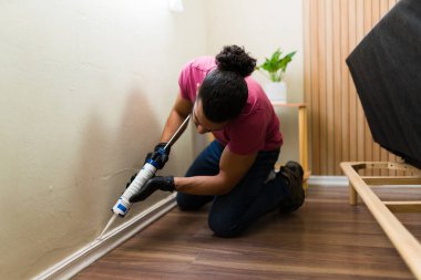 Latin tamirci yatak odasındaki süpürgeliğe kalas takıyor, ustalıkla ev onarımı yapıyor ve iç mekanları geliştiriyor.