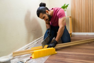 Eldiven kutusuyla odun kesmeye odaklanmış tamirci özenle ev onarımı yapıyor ve iç tasarımı geliştiriyor.