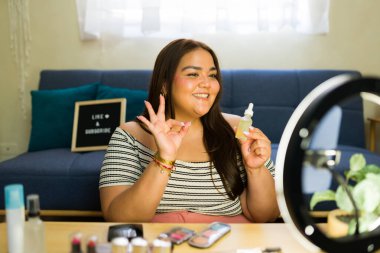 İçerik oluşturucu, video blogu için makyaj dersi sırasında güzellik ürünleri önerirken ok işareti yapıyor