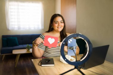 Vücut pozitifliği ve evde kendini sevme ile ilgili bir video blogu kaydederken kalp sembolü gösteren büyük boy bir etken