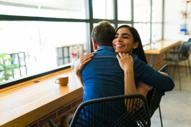 Genç Latin çift kahve dükkanında sarılıyor romantik bir buluşmanın tadını çıkarıyor, sevgi ve sevgi gösteriyor.