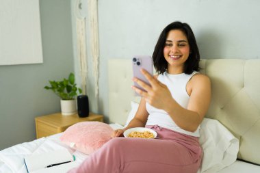 Yatakta kahvaltının keyfini çıkarırken akıllı telefonuyla uzaktan kumandayla rahatı kucaklıyor ve düzenli bir sabah rutini uyguluyor.