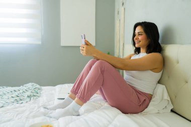 Ofisteki yatağında çalışırken cep telefonu kullanan serbest çalışan bir kadın.