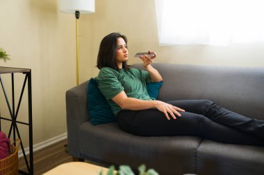 Rahat bir serbest çalışan, evden çalışırken telefonuyla sesli mesaj gönderiyor, esnek bir iş-yaşam dengesinin keyfini çıkarıyor.