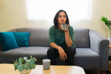 Freelancer evden çalışırken telefonuna sesli mesajlar kaydediyor. Oturma odasının keyfini çıkarıyor.