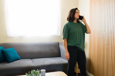 Genç bir kadın oturma odasından uzaktan iş görüşmesi yapıyor, telefon bazlı bir işin esnekliğinden zevk alıyor.