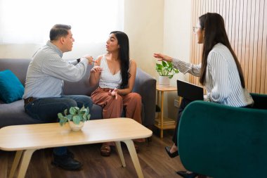 Kızgın çift modern bir ofiste çiftler terapisi sırasında bir psikologla tartışıyor ve sorunları tartışıyor.