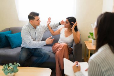 Latin çift, profesyonel psikologla çift terapisi seansı sırasında bir not defterine not alarak tartışıyor.