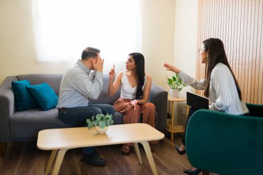 Çift terapisi sırasında aralarında arabuluculuk yapan profesyonel psikologla tartışan çift.