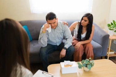 Profesyonel psikologla çift terapisi seansında karısından duygusal destek alırken, İspanyol koca ağlıyor ve mendille gözyaşlarını siliyor.