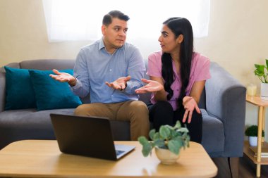 Latin çift sorunlarını evde dizüstü bilgisayar kullanarak online terapi sırasında psikologa anlatırken işaret veriyorlar.