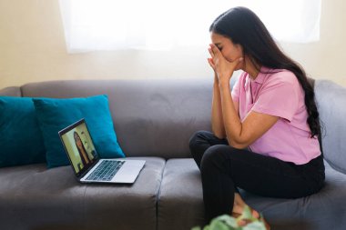 Üzgün kadın evinde bilgisayarından sanal terapi görüyor. Video aramasında psikologla konuşuyor.