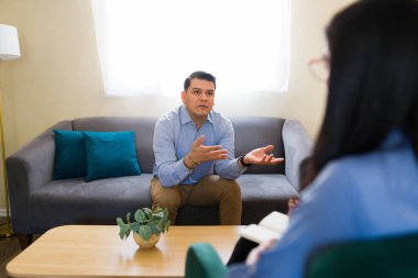 Psikologa ruh sağlığı sorunlarını anlatırken hasta hareketi terapi seansı sırasında not alıyor.