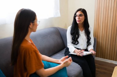 Psikolog, bir psikoterapi seansı sırasında hastasının akıl sağlığı hakkında konuşmalarını dinlerken not alıyor.