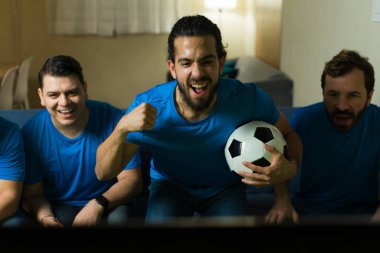 Heyecanlı taraftarlar evde maç izlerken golü kutluyor ve spora olan tutkularını ve coşkularını dile getiriyorlar.