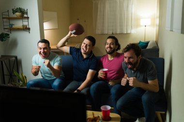 Heyecanlı erkek arkadaşlar evlerinde futbol maçı izlerken tezahürat ve içki yapıyorlar.